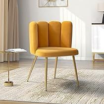 a yellow chair sitting on top of a wooden floor next to a white table and lamp