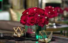 red roses and pearls in a green vase on a table with other decorative items around it