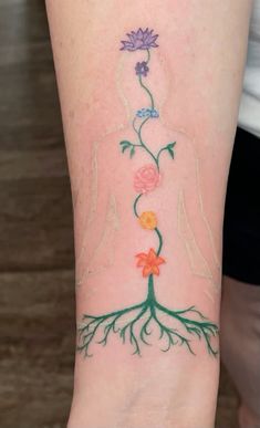 a woman's arm with a tree and flowers on it