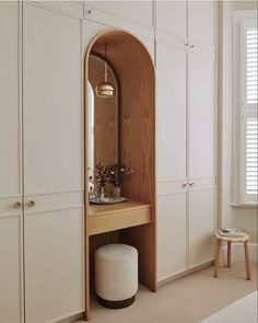 a room with white cupboards and a mirror on the wall next to a stool