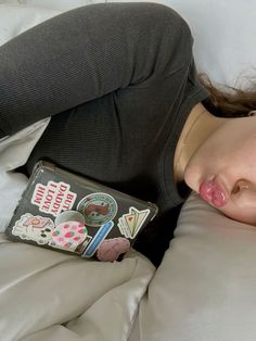 a woman laying on top of a bed with her eyes closed and head resting on the pillow