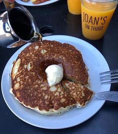 pancakes on a plate with butter and syrup being drizzled onto the top