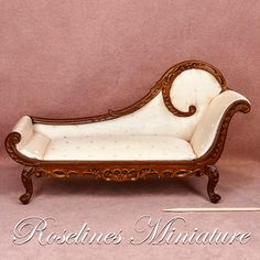 an antique wooden chaise lounge with white upholstered fabric and wood trimming