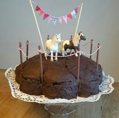 a chocolate cake decorated with horses and bunting on the top is sitting on a table