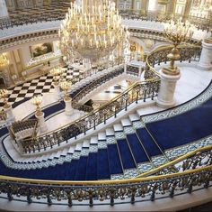 an ornate staircase with chandeliers and blue carpet