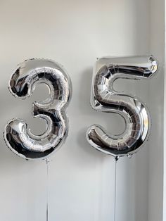 the number 55 is made out of silver foil and hangs on a wall with balloons