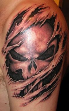 a man's arm with a skull and flames tattoo on the side of his shoulder