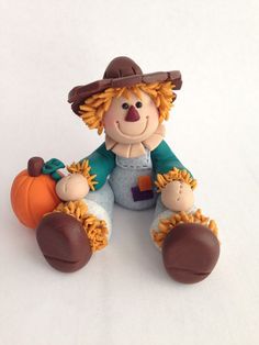 a small toy sitting on top of a white table next to a pumpkin and hat