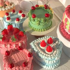 there are many different cakes on the table with strawberries and cherries on them