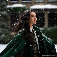 a woman wearing a green and black cloak in the snow