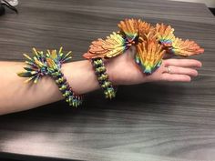 two colorful bracelets are on the palm of a person's hand, which is decorated with flowers and leaves