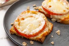 two pieces of bread with cheese and tomato on them are sitting on a black plate