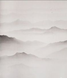 a black and white photo of foggy mountains