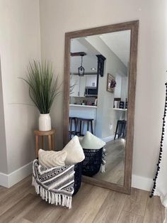 a large mirror sitting on top of a wooden floor next to a chair and potted plant