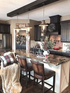 a large kitchen with wooden floors and black cabinets, along with an island in the middle