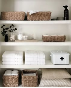 the shelves are filled with towels and other bathroom items in baskets on top of them