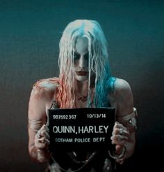 a woman with blue hair holding a sign that reads,'quinn harley gotham police dept '