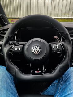 the interior of a car with steering wheel and black leather trims, including blue jeans