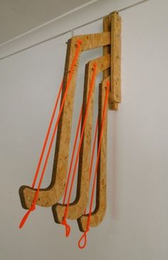 a wooden clock hanging from the side of a wall with orange strings attached to it