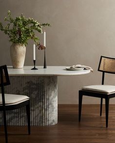 a table with two chairs and a vase on top of it next to a plant