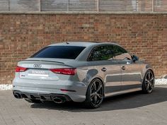 an audi car parked in front of a brick wall with black rims on it