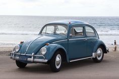 an old blue beetle parked on the beach