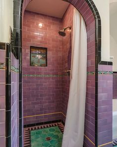 a bathroom with purple tiles and black trim around the shower area, along with a white curtain