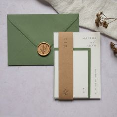 an envelope with a wax stamp on it next to a green and white card holder