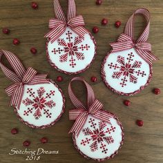 three red and white ornaments with bows on them sitting on top of a wooden table