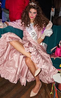 a woman in a pink dress is sitting on a green couch wearing a tiara