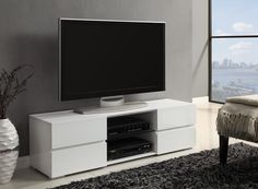 a white entertainment center with a flat screen tv on it's stand in front of a large window