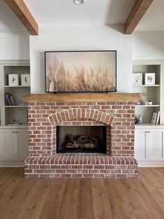 a living room with a brick fireplace and bookcases on the wall above it