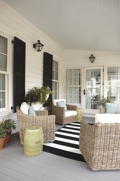 wicker furniture on a porch with black and white striped rug in the foreground