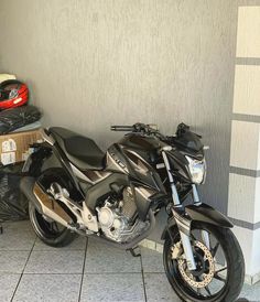 a motorcycle is parked in front of a wall and some boxes on the floor next to it