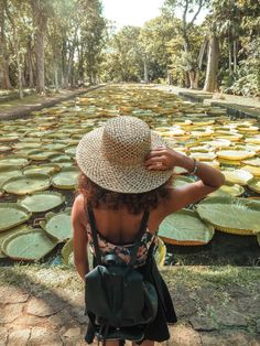 a woman wearing a hat standing in front of water lillies at the botanical garden