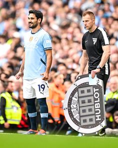 two soccer players standing next to each other in front of a crowd with people watching