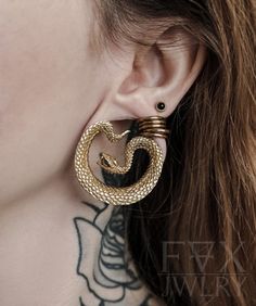 a close up of a person with tattoos on their neck and behind them is a pair of earrings