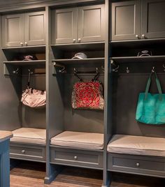 the inside of a walk - in closet with gray cabinets and white cushioned benches