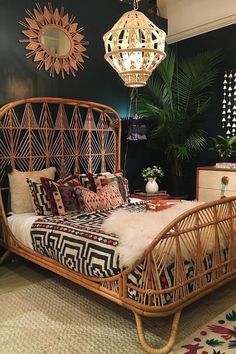 a rattan bed frame with pillows and blankets on it in a room decorated with plants