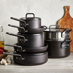 pots and pans are stacked on top of each other in front of a cutting board