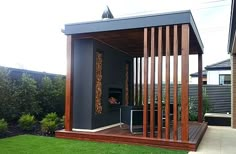 an outdoor living area with a grill and grass in the back yard, next to a house