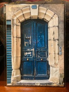 an old blue door is in front of a stone building with shutters and arched doorway