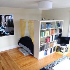 a room with a bed, bookshelf and pictures on the wall in it