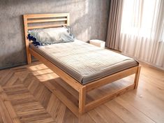 a bed sitting on top of a hard wood floor next to a window with curtains