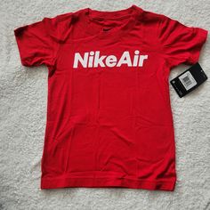 a red shirt with the word nike on it next to a small black cell phone