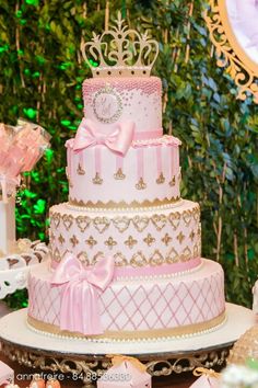 a three tiered cake with pink and gold decorations on the top is surrounded by other desserts