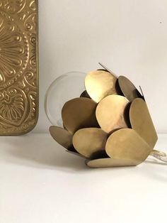 a vase filled with lots of gold colored discs next to a golden phone case on a white surface