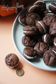 chocolate cookies with white frosting on a plate next to a penny and orange background