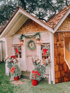 two christmas wreaths on top of potted plants in front of a house