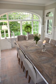 a dining room table with candles on it in front of an arched window that overlooks the garden